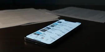 Smartphone displaying social media content on desk with legal documents, dramatic investigative lighting