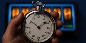 Analog stopwatch against digital slot machine background symbolizing manual timing testing methods