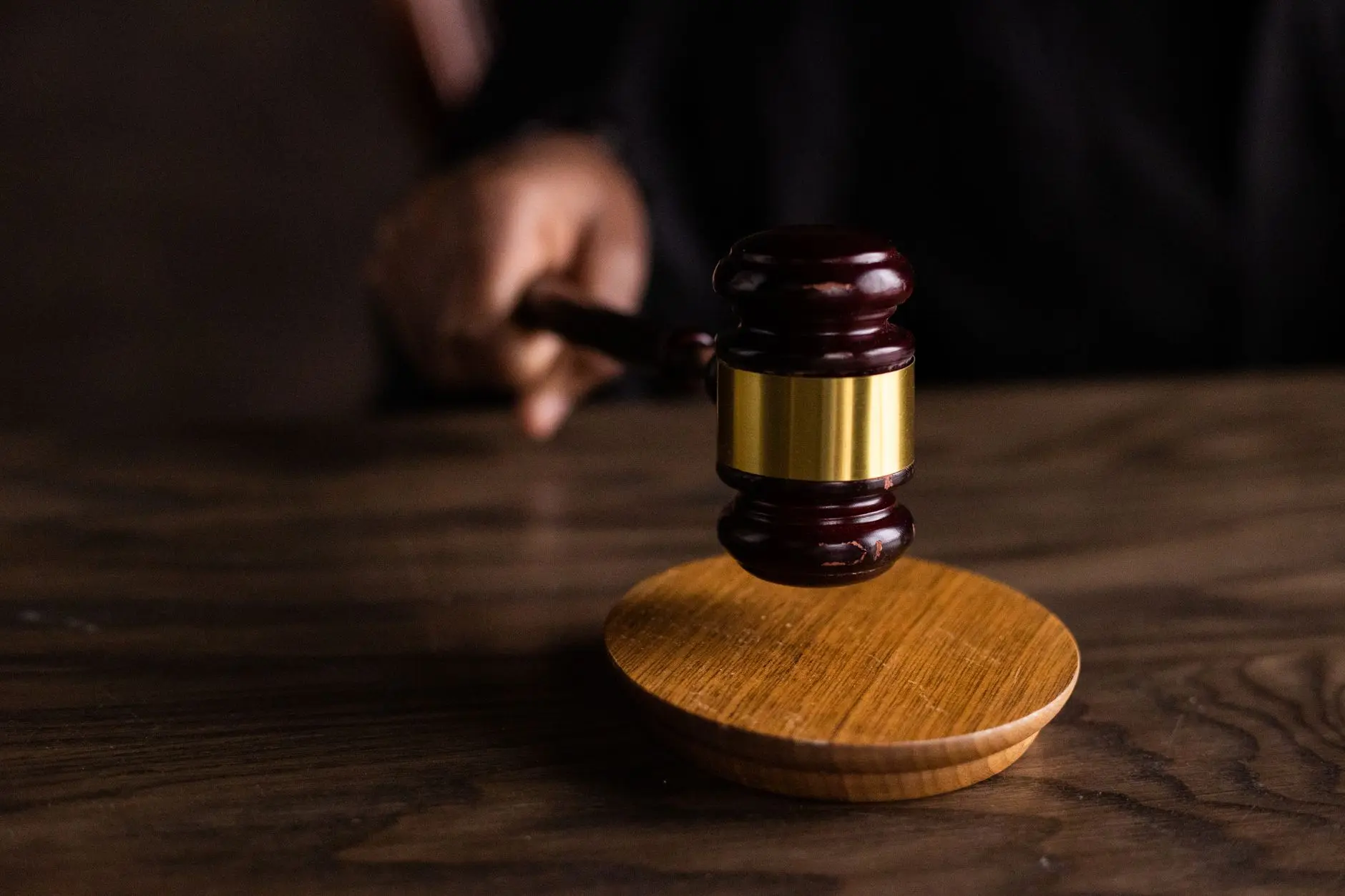 Wooden gavel above a circular wooden sound block on a table.