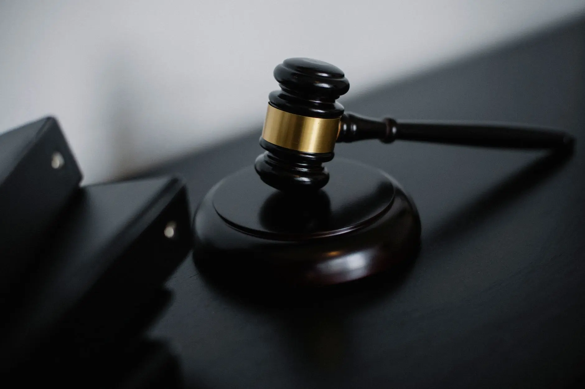 Close-up of a wooden gavel with a gold band on a dark surface.