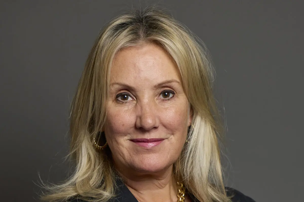 Portrait of a woman with blonde hair, wearing a black blazer and earrings.