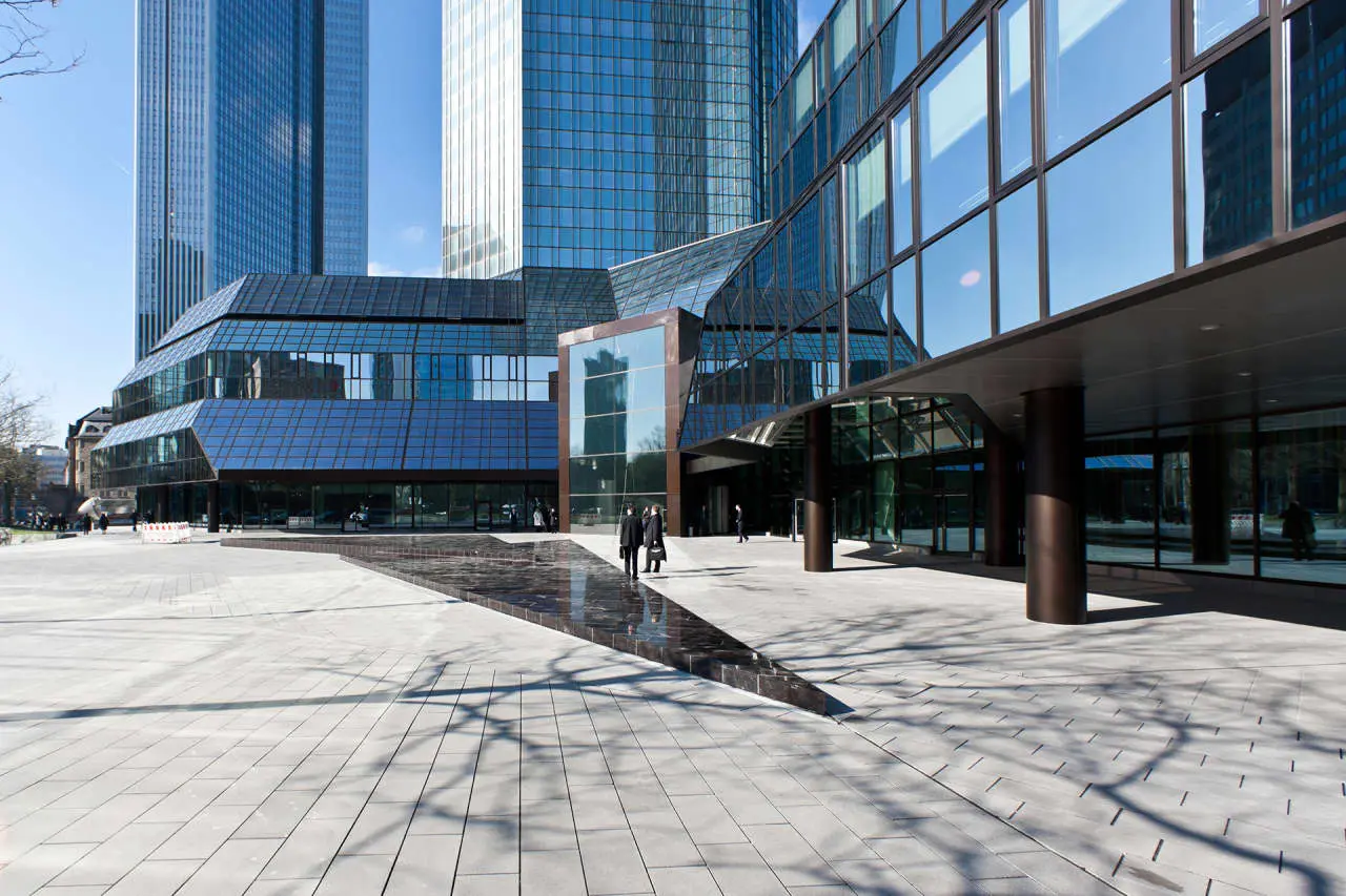 Modern glass and steel architecture of the Deutsche Bank headquarters towers in Frankfurt.