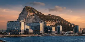 Rock of Gibraltar with modern financial district buildings representing regulatory innovation