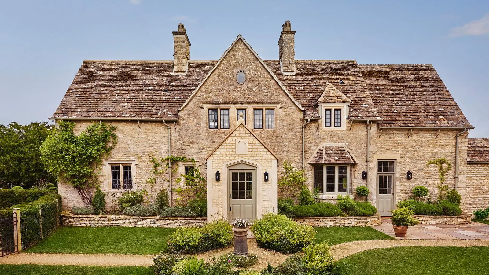 Beautiful stone house with manicured gardens and clear blue sky.