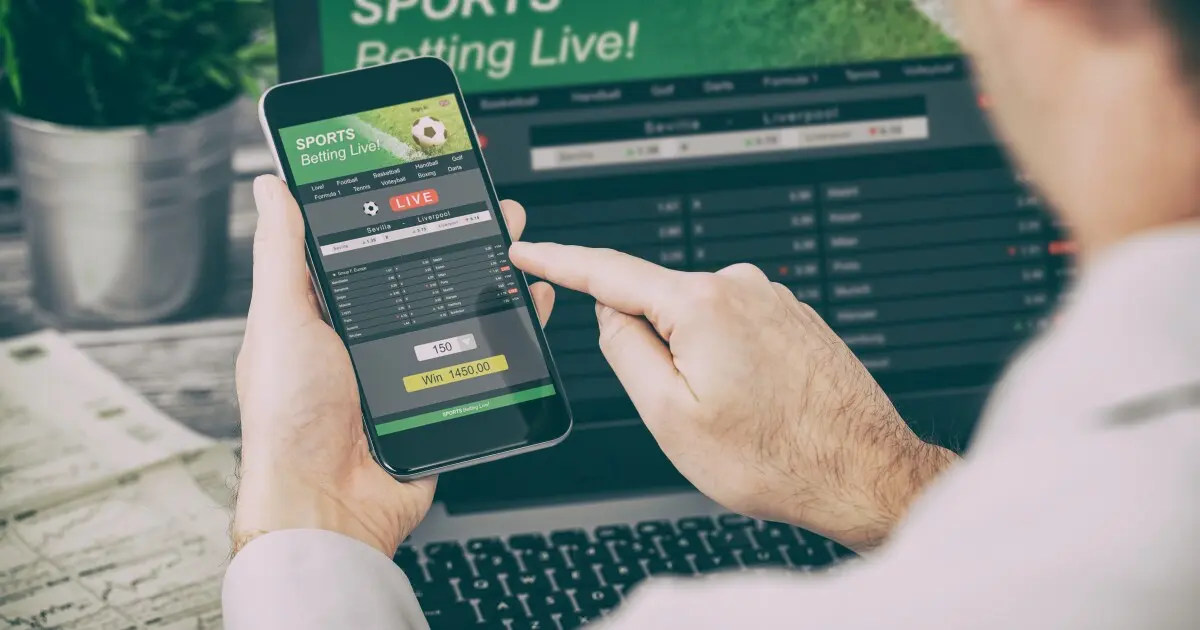 A person using a smartphone for live sports betting during a match.