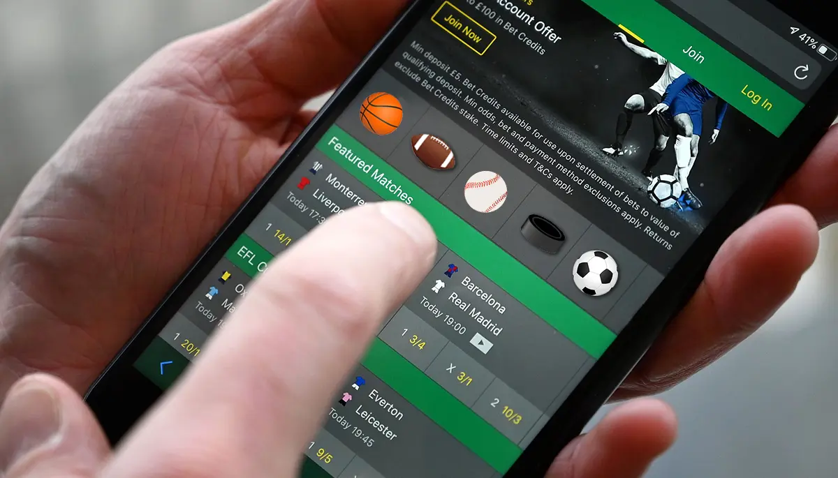 Close-up of a person using a sports betting app on a smartphone showing soccer and football match odds