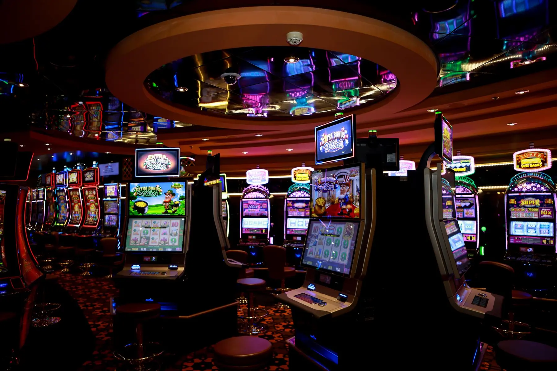 Brightly lit casino with multiple slot machines visible.