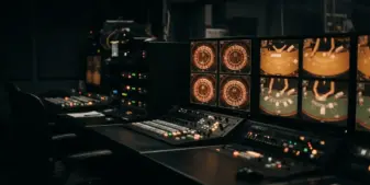 Live casino studio control room with monitoring screens showing gaming tables and warning lights
