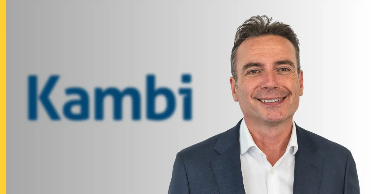 A man in a suit smiling, with 'Kambi' logo in the background.