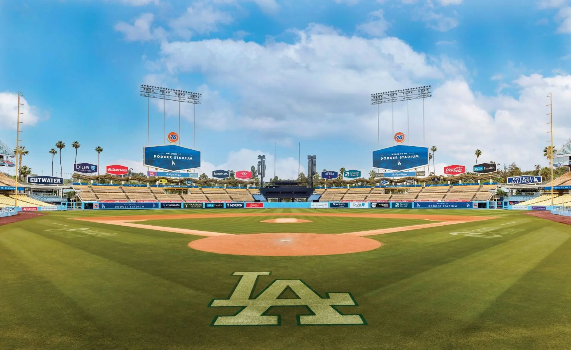 Wide view of the empty field at Dodger Stadium with the LA logo on the grass and scoreboard signs.