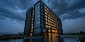 Modern corporate headquarters building at dusk with illuminated windows against darkening sky