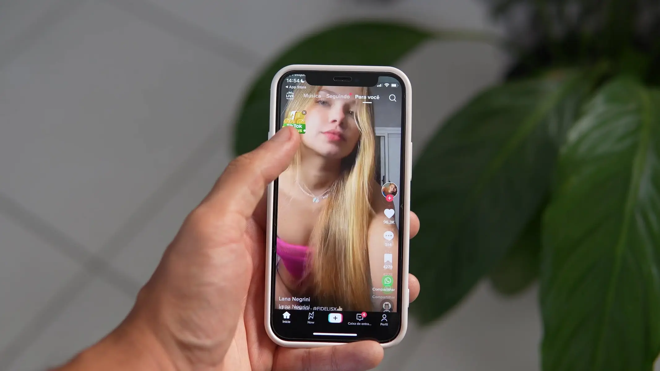 A person holding a smartphone displaying a TikTok profile page of a woman