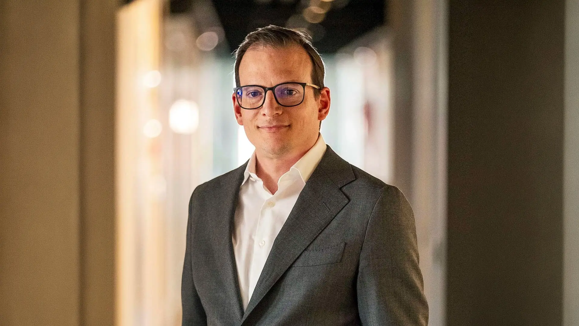 Portrait of Pierre Tournier wearing glasses and a grey suit jacket over a white shirt.