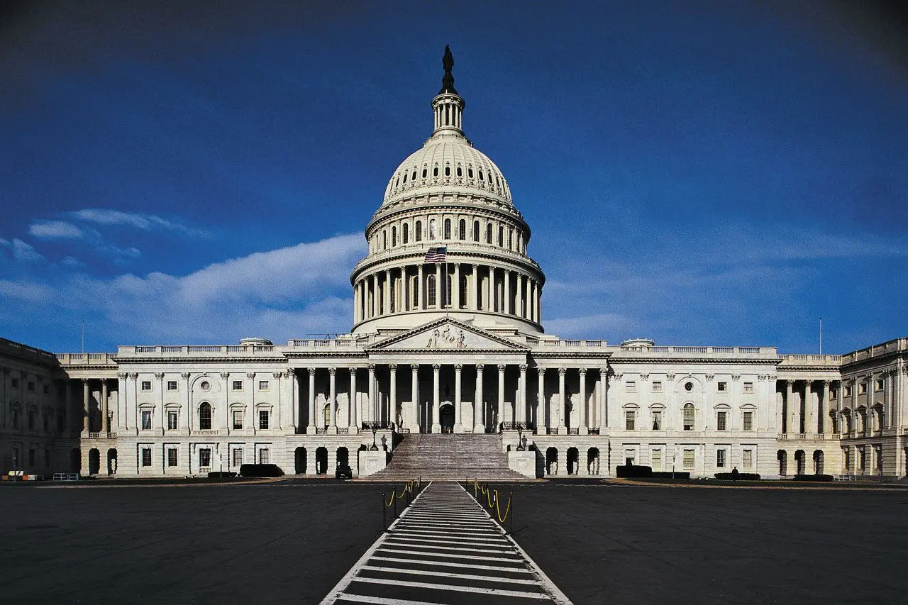 Front view of the United States Capitol building with its white dome and columns under a clear blue sky