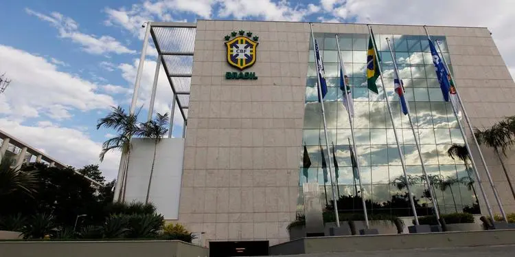 The exterior of the Brazilian Football Confederation headquarters featuring the CBF logo and Brazilian flags.