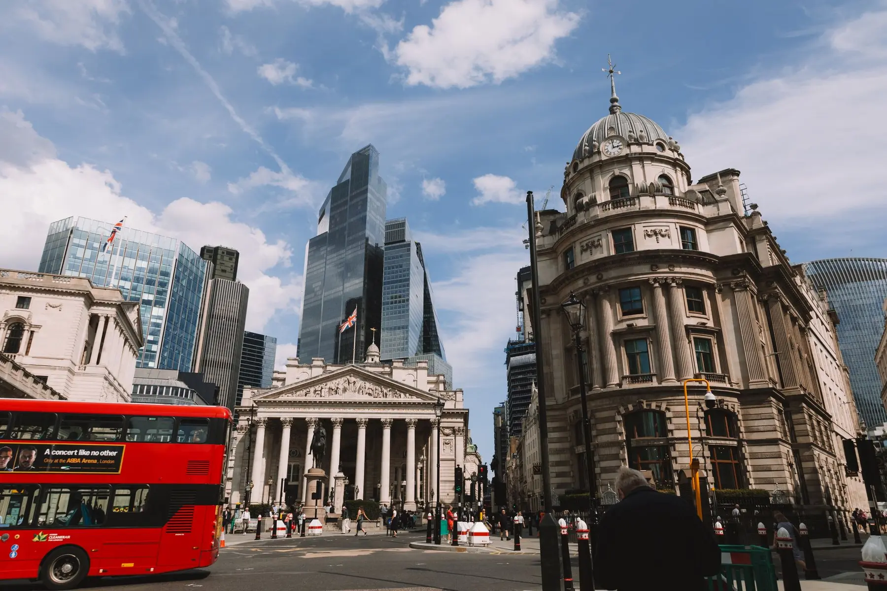 City of London street scene featuring the Royal Exchange and the towering skyscrapers of the financial district.