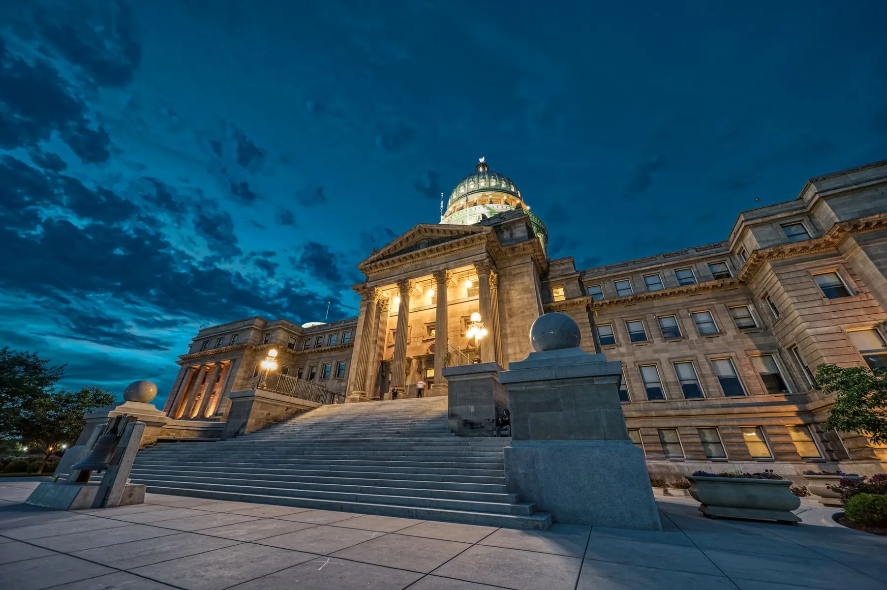 Wide evening view of the Oklahoma State Capitol building with its illuminated dome and grand stone staircase.