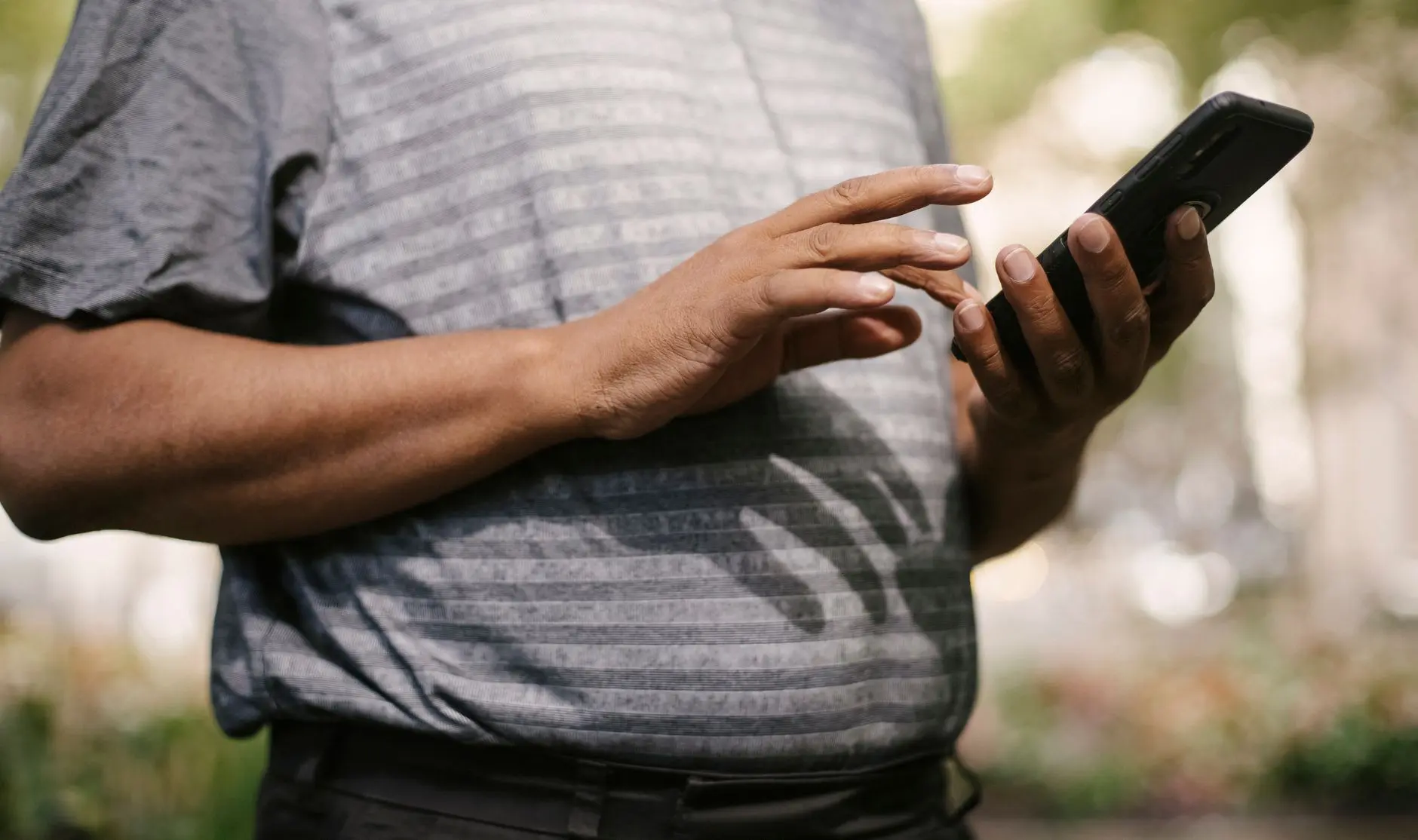 Close-up of a person using a black smartphone outdoors