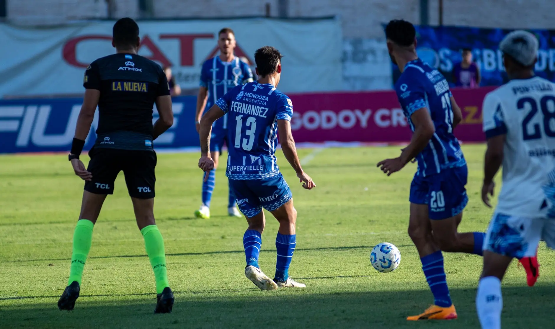 Soccer players in blue and white jerseys during a match, featuring various kit sponsors.
