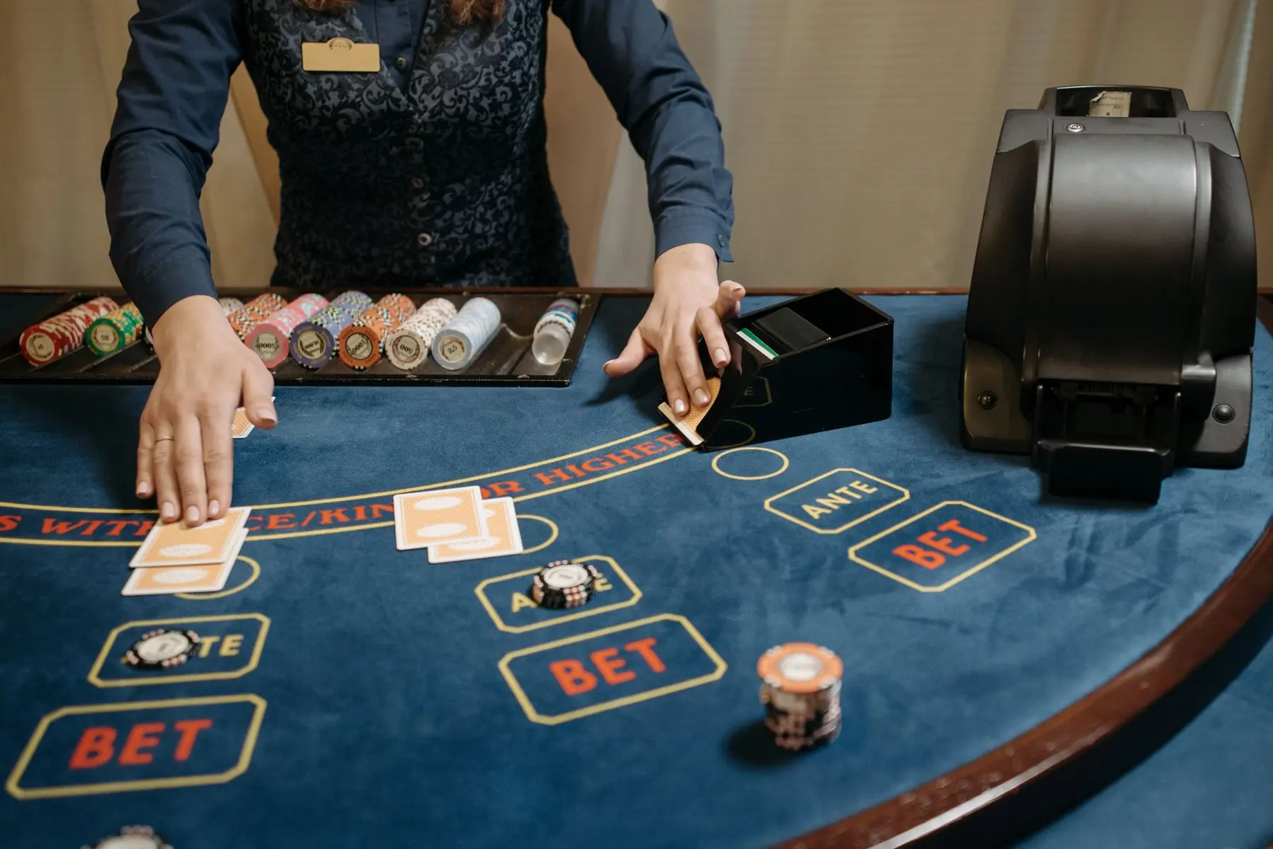 A casino dealer managing a card game table with chips and a card shuffler