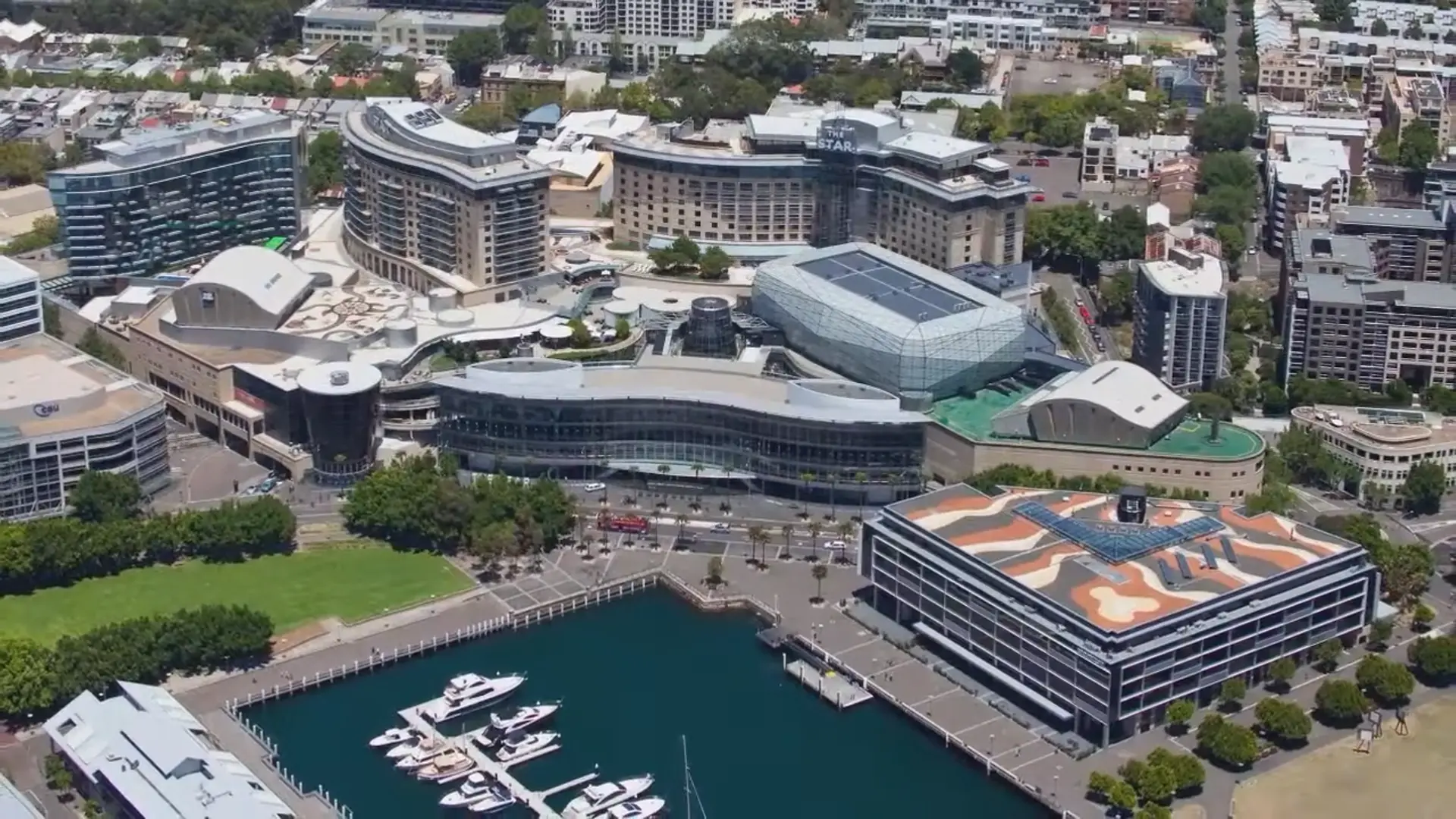 Aerial view of The Star casino and hotel complex in Sydney, overlooking the harbor with docked yachts.