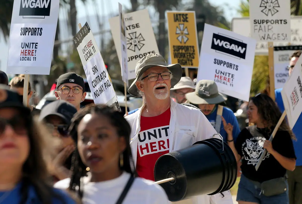 Protesters holding signs supporting UNITE HERE Local 11 and WGAW during a strike picket.