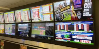 Betting shop screens behind a counter in a British bookmaker